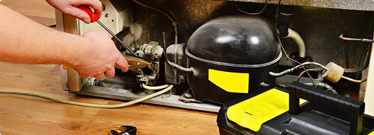 Refrigerator repair technician fixing the compressor and wiring in Huntington Park, CA