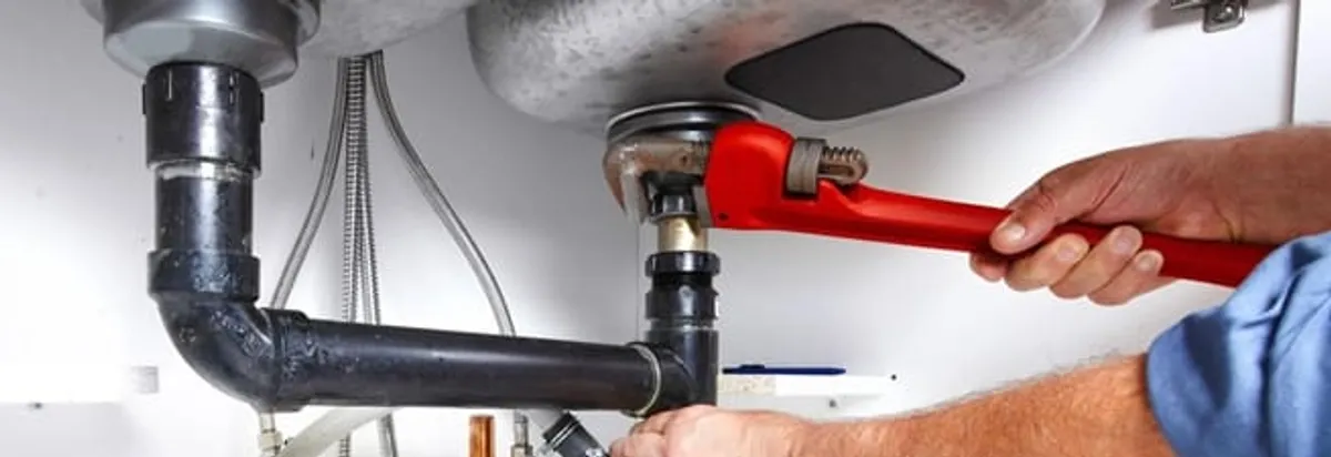 Garbage disposal repair technician tightening the sink drain and disposal connection in Los Angeles, CA