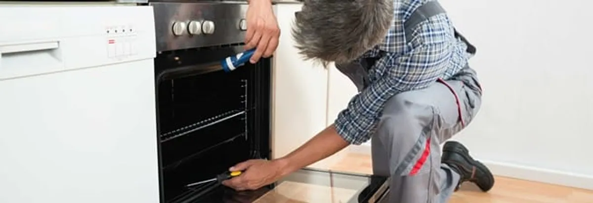Oven repair technician inspecting and servicing an electric oven in Los Angeles, CA