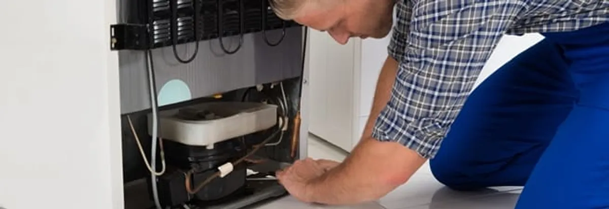 Refrigerator repair technician servicing the compressor and condenser area in Los Angeles, CA