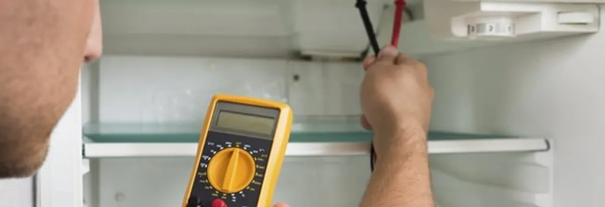 Refrigerator repair technician testing electrical components with a multimeter in Los Angeles, CA